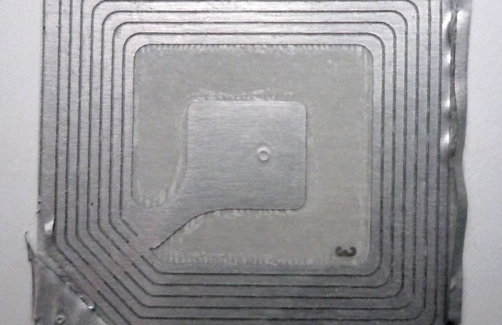 Close-up of an RFID inlay — antenna coil and chip — for item-level apparel tagging mandate compliance.