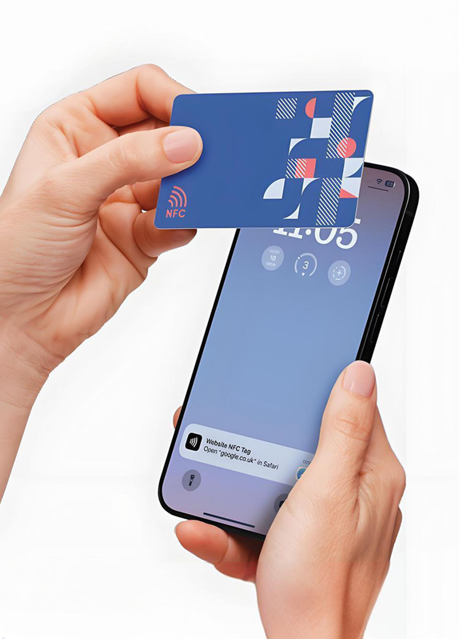 Hand tapping a blue printed NFC card on a smartphone showing a website tag notification