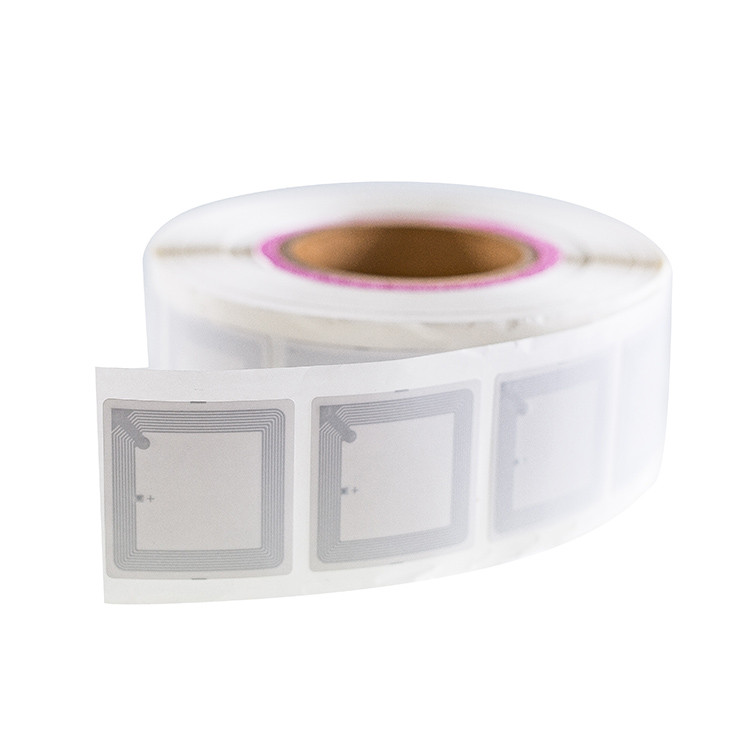 Roll of square white RFID labels with visible antenna coils on a white background