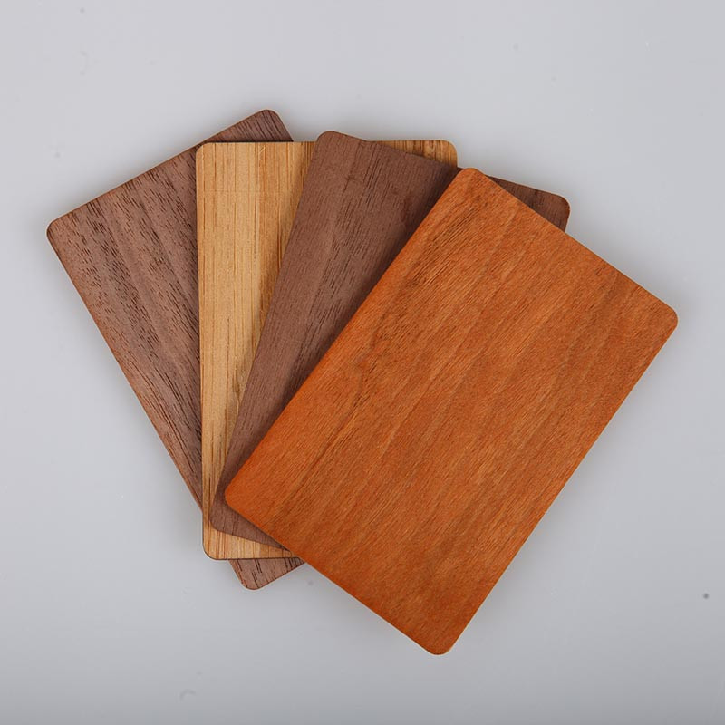 Four blank wooden NFC cards in different wood grains fanned on a gray background